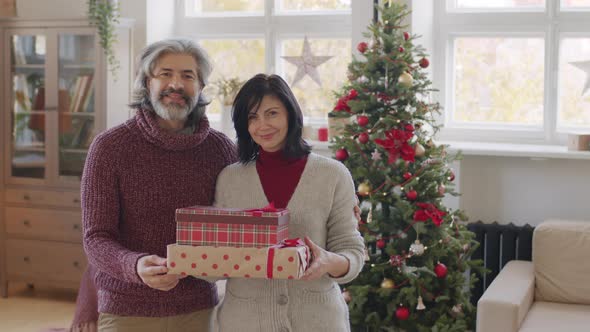 Happy Mature Couple with Christmas Presents Posing at Home