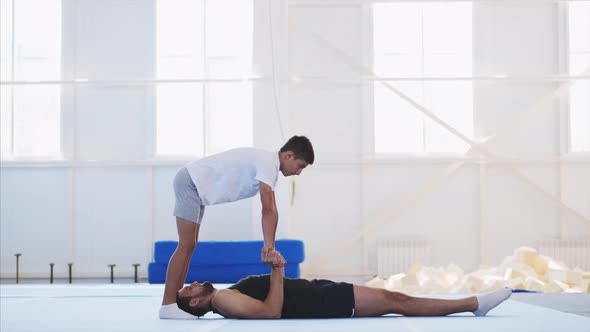 A Fit Man and a Teenager are Practicing Acrobatic Handstand in Gym