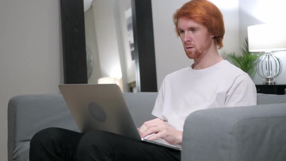 Redhead Man Excited for Success Working on Laptop