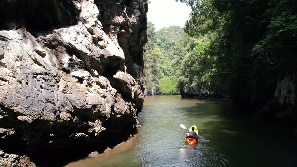 a kayaker paddling around a limestone rock on a river in Ao Thalane Krabi Thailand surrounded by man