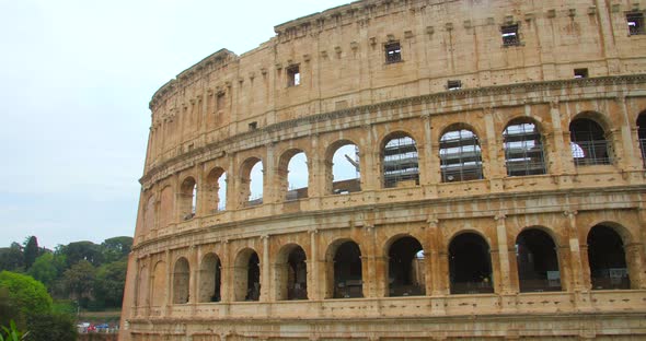 Antique Colosseum With People Strolling During Daytime In Rome, Italy. Tilt-down