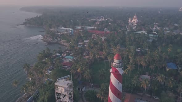 Thangassery Lighthouse in stunning Indian coastal landscape at sunset, Kerala, India. Aerial drone v