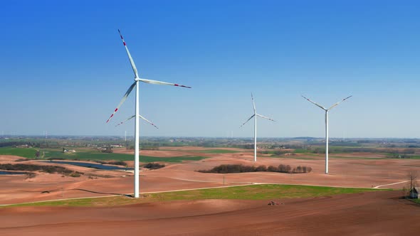 Large wind farms in the field with a small plowing tractor