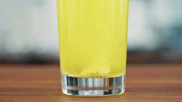 Effervescent Tablets Vitamin C Nutritional Supplements in Glass with Yellow Carbonated Water Sport