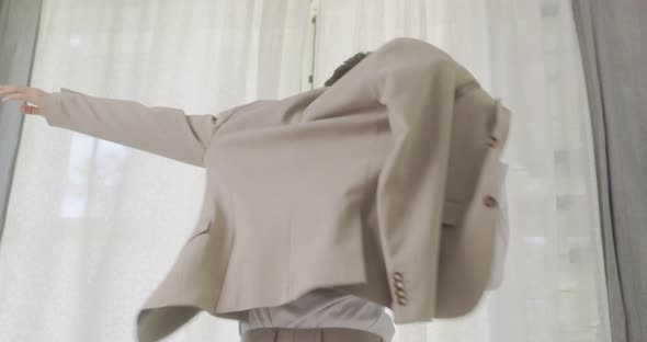 Handsome Man Puts Suit On During Morning Wedding Day. Young Groom Standing In Front Of The Window.