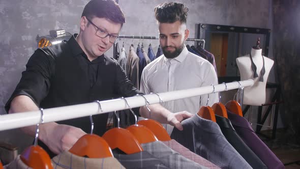 Seller in the Costume Shop Helps the Young Man To Choose a Suit