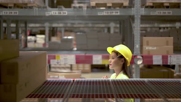 Asian woman warehouse worker checks stock and inventory with digital tablet computer