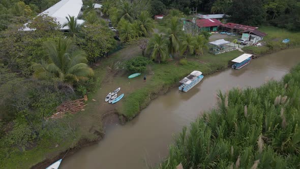 Man standing between kayaks and boats at the shore of rio cotos near Manuel Antonio, Costa Rica. Aer