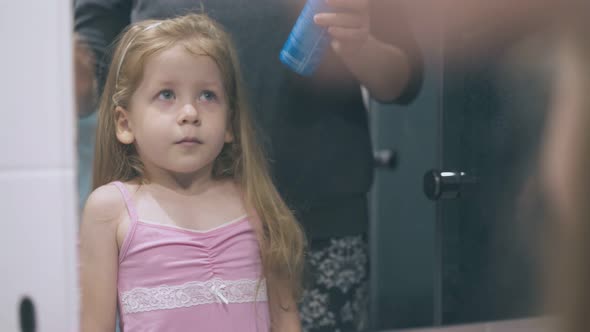 Pretty Girl and Mom with Bottle for Rinsing Nose at Mirror