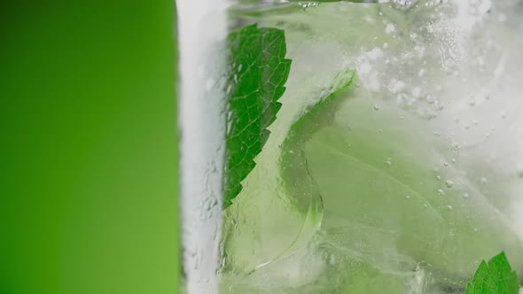 Soda Water is Being Poured in Slow Motion to the Highball Glass with Mojito Ingredients Making the