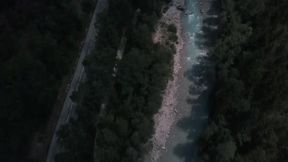 Aerial dron pan up shot. Starts with a shady glacier river next to a road and pans up to a bird eye