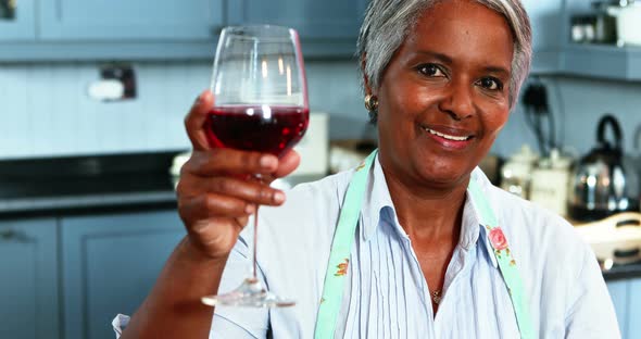 Senior woman having wine in kitchen