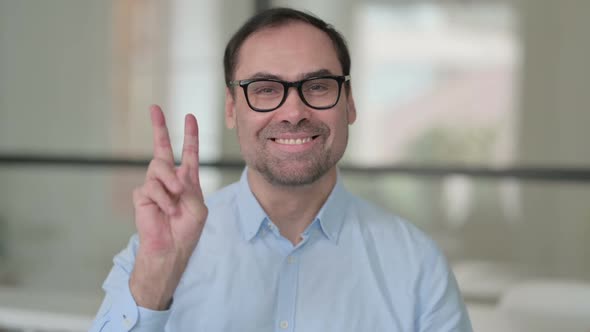 Portrait of Positive Middle Aged Man Showing Victory Sign