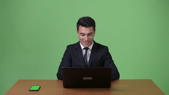 Young Handsome Hispanic Businessman Against Green Background