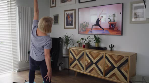 Video of active senior woman exercising in front of TV. Shot with RED helium camera in 8K.