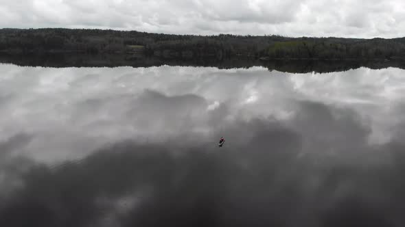 One Alone Canoe Boat on Calm Lake with Cloud Reflection Aerial