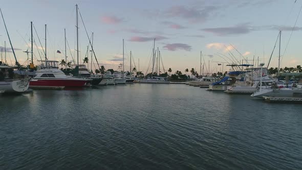 Drone flying low between boats and yachts on marina during sunset