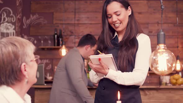 Pretty Waitress Taking an Order From Senior Woman