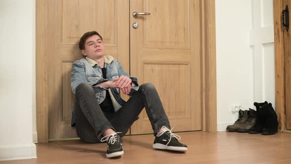 tired and upset man comes home and sits on the floor in frustrated feelings