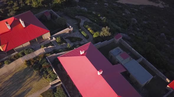 Aerial shot of red roof properties on the hill with two beaches and ocean view next to a lighthouse.