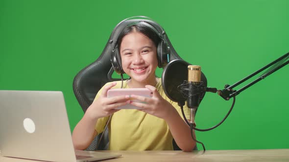 Excited Asian Kid Girl Playing Video Game With Phone Then Smiles To Camera While Live Stream