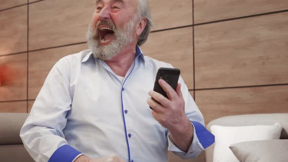 happy bearded grandfather winner celebrate victory success read good news in cell text message. Over