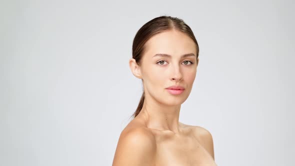 Beautiful Young Woman with Clean Fresh Skin Standing Over Light Grey Background