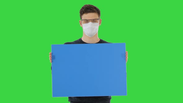 Young Man in Medical Mask Showing and Displaying Placard on a Green Screen, Chroma Key