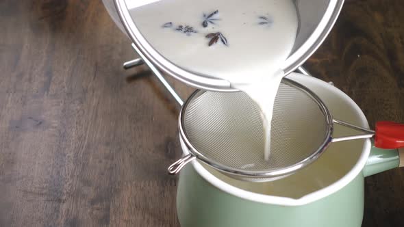 Milk mixture being poured to drain in mesh stainless steel colander