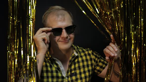 Portrait of Caucasian Man Posing on Black Background. Gold Shining Foil Strips. Party, Music, Disco