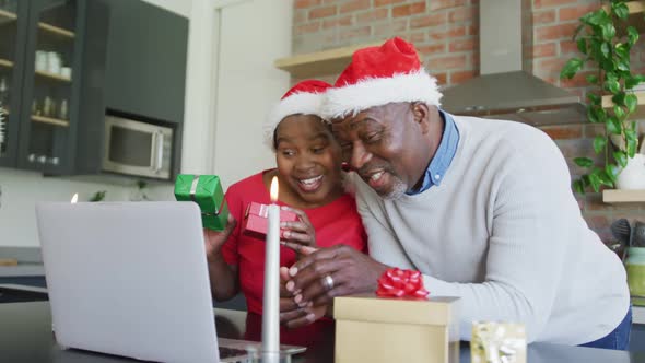 Happy african american senior couple in santa hats on video call on laptop at christmas time