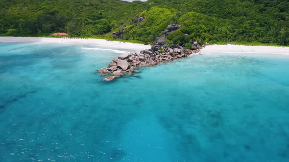 Aerial Footage Approaching Unique Granite Boulders Surrounded By Crystal Clear Turquoise Blue Ocean