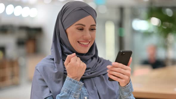 Arab Woman Celebrating Success on Smartphone 