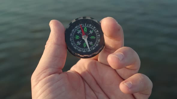 Detail of a Man's Hand with a Compass in the Sea