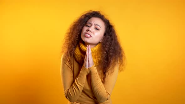 Cute Curly Young Girl Praying Over Yellow Background, Woman Begging Someone