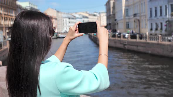 Smiling Travel Woman Enjoying Shooting Video of Water Canal and Cityscape From Embankment in