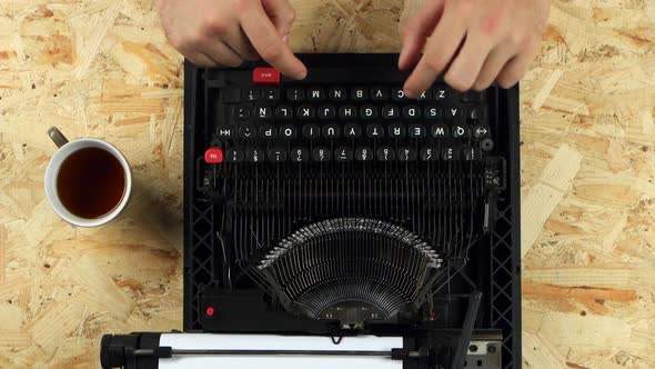 Men's Hands Type the Text of the Book on a Typewriter. View From Above