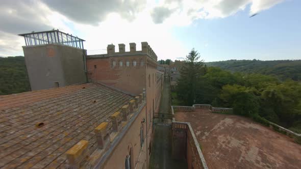 Flock Of Pigeons Flying On Traditional And Brick Buildings In Sinalunga, Siena, Italy. - FPV, Aerial