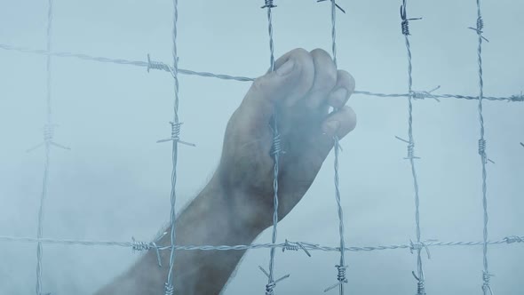 Hand On Prison Wire With Passing Smoke