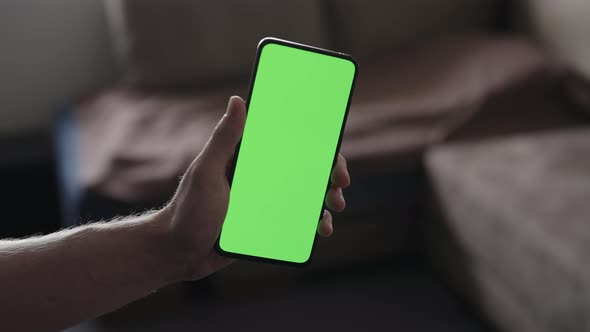 Man Use Smartphone with Green Screen While Standing in Living Room