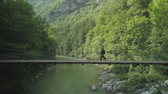 Aerial view of woman traveler walking on the bridge under Tara river in Montenegro