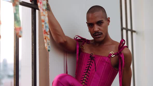 Male Dancer in Pink Bodice By Barred Window Looking Into Camera