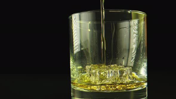 Macro Shot in Slow Motion of a Drink Being Poured on a Glass. Background Is Black. 