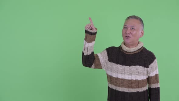 Happy Mature Japanese Man Talking While Pointing Up