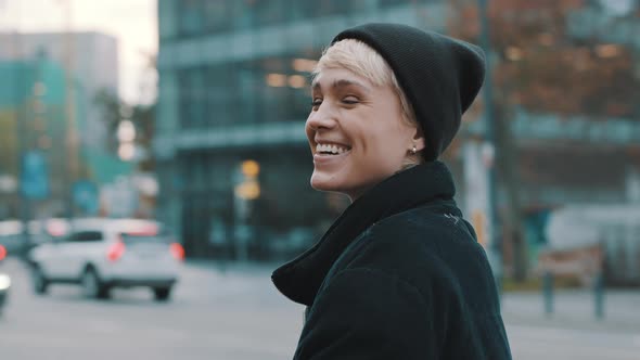 Portrait of Young Smiling Woman with Black Hat and Winter Jacket in the City 