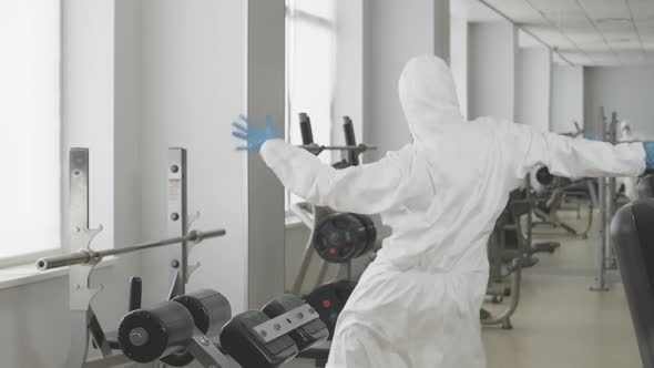 Funny Dance of Positive Caucasian Woman in Protective Suit and Respirator in Gym. Portrait of