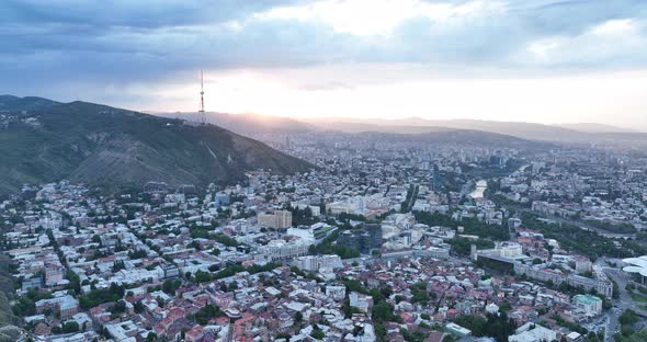 Aerial view of center of Tbilisi under Mtatsminda mountain at sunset. Georgia 2022 summer