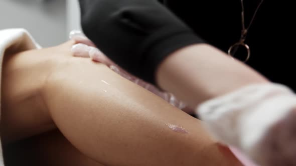 Waxing Procedure  Depilation Master Rips Off a Strip of Wax Off the Female Leg