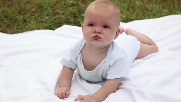 Cute Little Newborn Girl Lying on Tummy on Blanket in Lawn on Sunny Summer Day Outdoor