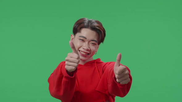 Happy Asian Transgender Male Showing Thumbs Up Gesture While Standing In The Green Screen Studio